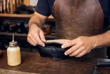 Sapateiro em Campo Grande realizando colagem de solas descoladas em um par de sapatos.
